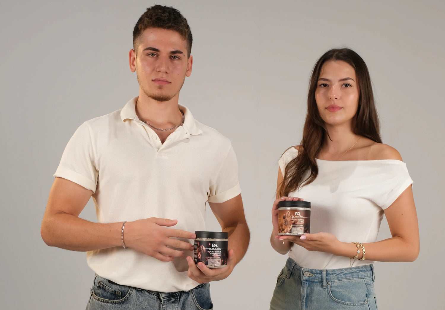 Two people standing side by side holding Black Red brand face scrub against a plain background
